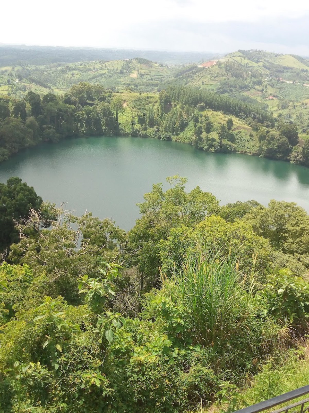 A deep green crater lake ringed by forest and farmland near Fort Portal